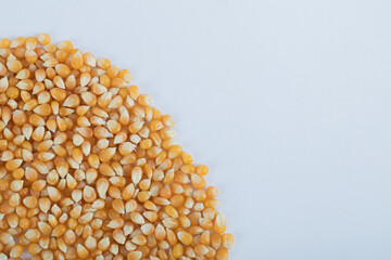 Heap of uncooked corn grains on a white background