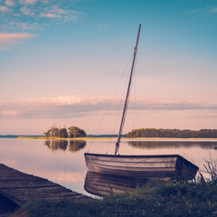 Fototapeta Drewniana łódź stojąca nad brzegiem jeziora obraz