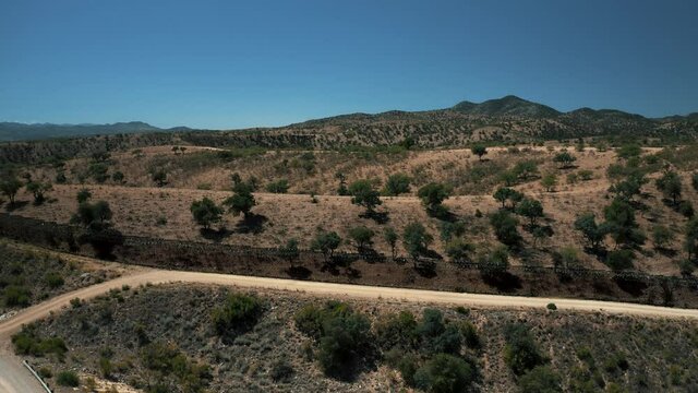 Aerial View Of Nogales Border Area Showing Border Fence Separating The United States Of America And Mexico With U.S. Border And Customs Protection Patrolling Border Area With Their Vehicles