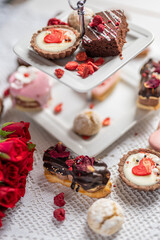 beautiful tasty romantic selection of pink chocolate love heart shape cakes for wedding, mothers day,  valentines day, spring flower biscuits tartlet and rose petals 