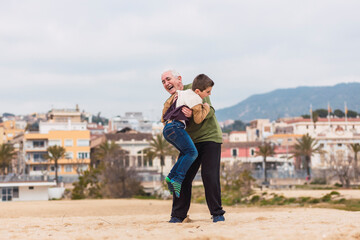 Grandfather holding his grandson on the beach