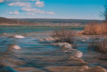 Huge waves caused by the wind on a large lake near the forest. reed beach at a dam for hydroelectric power in spring