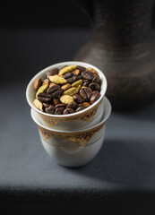 Roasted coffee beans with cardamom pods placed in a traditional Arabic coffee cups. Food photography of popular arabic drink- Qahva.