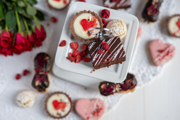 beautiful tasty romantic selection of pink chocolate love heart shape cakes for wedding, mothers day,  valentines day, spring flower biscuits tartlet and rose petals 