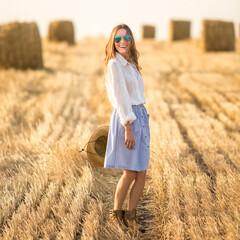 girl in a wheat field wearing hat and sunglasses