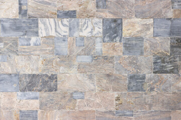 Fototapeta premium The wall of the building is faced with polished marble slabs of various colors and sizes.