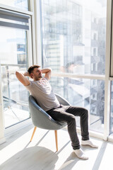 Rear view of man relaxing on chair at home near window