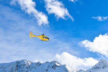 Rescue helicopter flys above the snow-capped mountains