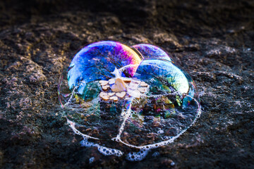 viele kleine Herzen aus Holz in mehreren Seifenblasen worin sich Farben des Regenbogen spiegeln - eine Fotoidee und Experiment als Symbol für Gemeinschaft und Zusammenhalt