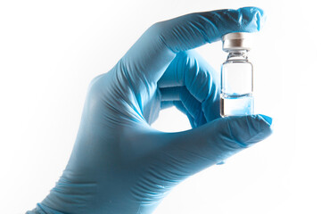 Medical theme: doctor's hand in a blue glove holding a vial of transparent liquid for injection