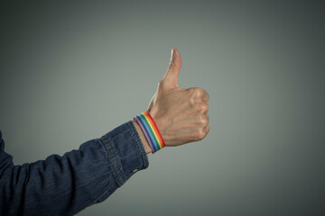 man hand with rainbow bracelet with thumb up