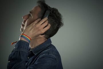 young man with rainbow bracelet listening to music with headphones