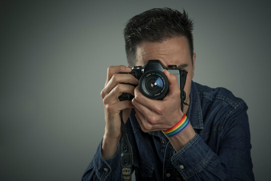 young man with rainbow bracelet taking a picture with camera