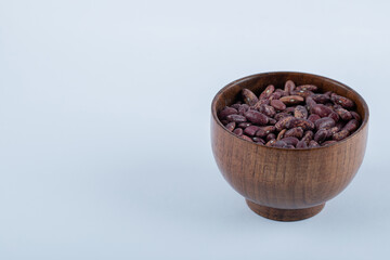 Heap of uncooked dried red beans in wooden bowl