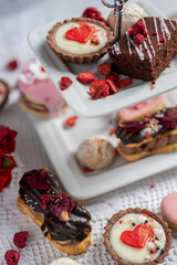 beautiful tasty romantic selection of pink chocolate love heart shape cakes for wedding, mothers day,  valentines day, spring flower biscuits tartlet and rose petals 