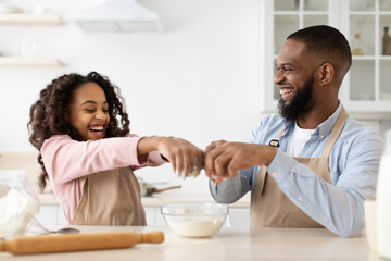 Fototapeta na wymiar Happy black man and his daughter preparing dough