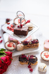 beautiful tasty romantic selection of pink chocolate love heart shape cakes for wedding, mothers day,  valentines day, spring flower biscuits tartlet and rose petals 