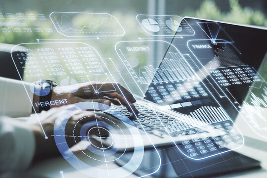Double exposure of abstract creative statistics data hologram with hands typing on laptop on background, analytics and forecasting concept