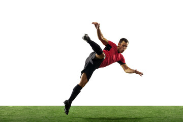 Powerful, flying above the field. Young football, soccer player in action, motion isolated on white background with green grass. Concept of sport, movement, energy and dynamic, healthy lifestyle.