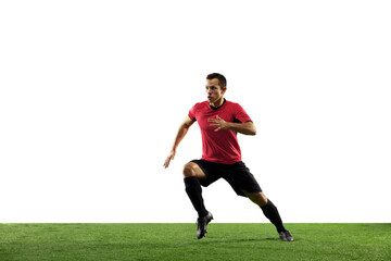 Powerful, flying above the field. Young football, soccer player in action, motion isolated on white background with green grass. Concept of sport, movement, energy and dynamic, healthy lifestyle.