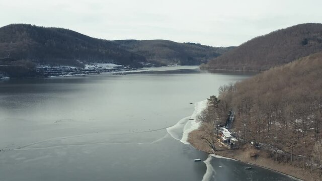 Drone Aerial views of the Keller National Park in Winter. The barrier lake Edersee is partly frozen. The Ederstausee is located in Hesse near the town Waldeck in Germany, Europe.