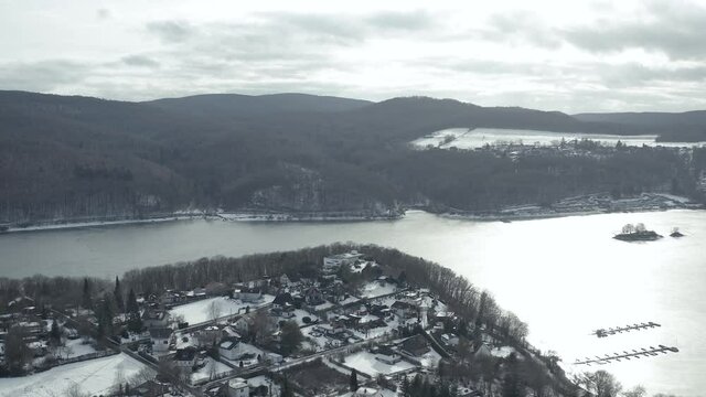 Drone Aerial views of the Keller National Park in Winter. The barrier lake Edersee is partly frozen. The Ederstausee is located in Hesse near the town Waldeck in Germany, Europe.