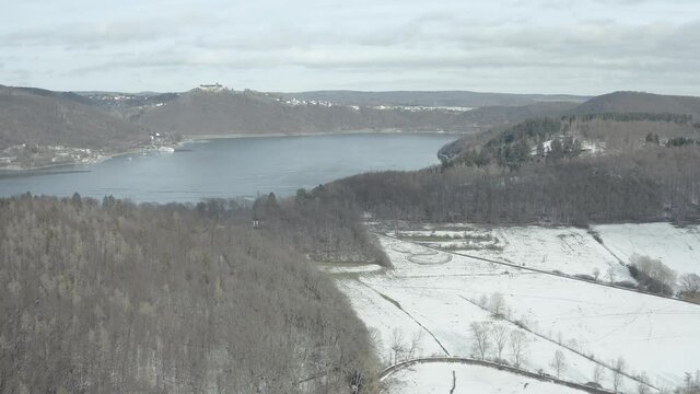 Drone Aerial views of the Keller National Park in Winter. The barrier lake Edersee is partly frozen. The Ederstausee is located in Hesse near the town Waldeck in Germany, Europe.