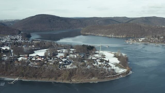 Drone Aerial views of the Keller National Park in Winter. The barrier lake Edersee is partly frozen. The Ederstausee is located in Hesse near the town Waldeck in Germany, Europe.