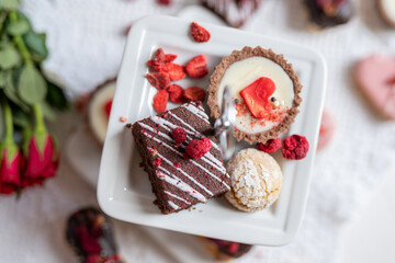 beautiful tasty romantic selection of pink chocolate love heart shape cakes for wedding, mothers day,  valentines day, spring flower biscuits tartlet and rose petals 