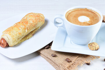 Cup of Colombian coffee, accompanied by baked bakery on white wooden background