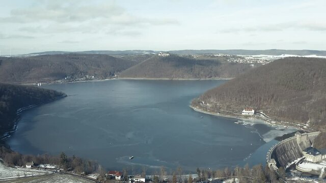 Drone Aerial views of the Keller National Park in Winter. The barrier lake Edersee is partly frozen. The Ederstausee is located in Hesse near the town Waldeck in Germany, Europe.
