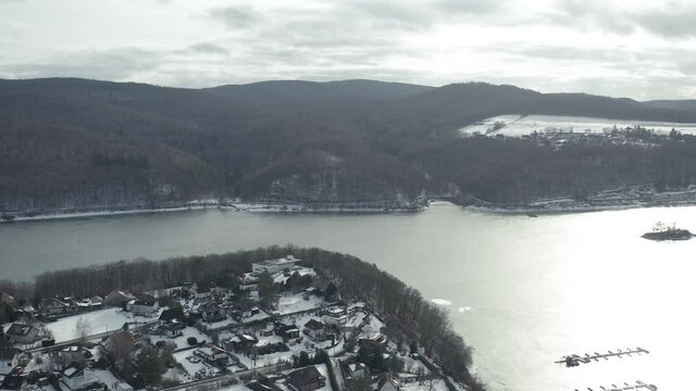 Drone Aerial views of the Keller National Park in Winter. The barrier lake Edersee is partly frozen. The Ederstausee is located in Hesse near the town Waldeck in Germany, Europe.