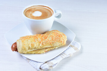 Cup of Colombian coffee, accompanied by baked bakery on white wooden background