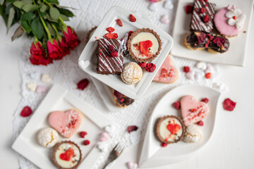beautiful tasty romantic selection of pink chocolate love heart shape cakes for wedding, mothers day,  valentines day, spring flower biscuits tartlet and rose petals 