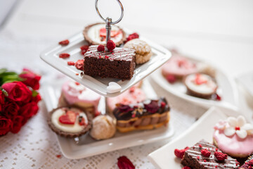 beautiful tasty romantic selection of pink chocolate love heart shape cakes for wedding, mothers day,  valentines day, spring flower biscuits tartlet and rose petals 