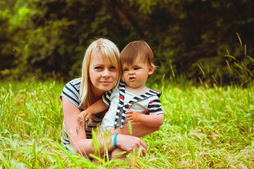 Fototapeta premium Happy family concept. Mother and son are playing in the playground and laughing on a summer walk on a sunny day. Family holiday and togetherness, selective focus
