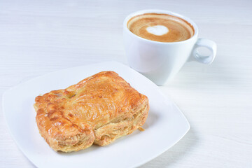 Cup of Colombian coffee, accompanied by baked bakery on white wooden background