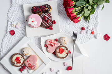 beautiful tasty romantic selection of pink chocolate love heart shape cakes for wedding, mothers day,  valentines day, spring flower biscuits tartlet and rose petals 