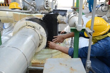 Worker use sealants for duct sealing and bonding metal sheet and insulation to protection pipeline in chemical plant.