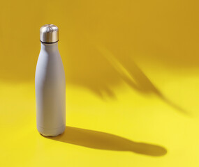 Grey reusable steel bottle on yellow background