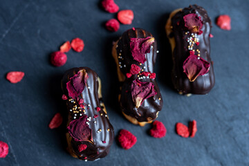 creamy chocolate eclair with edible flowers rose petals, romantic sweet dessert valentines day,...