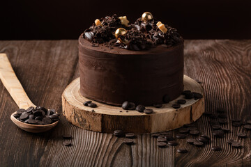 front view of chocolate cake, with chocolate chips, spoon and wooden table.