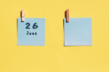 June 26st . Day of 26 month, calendar date. Two blue sheets for writing on a yellow background. Top view, copy space. Summer month, day of the year concept