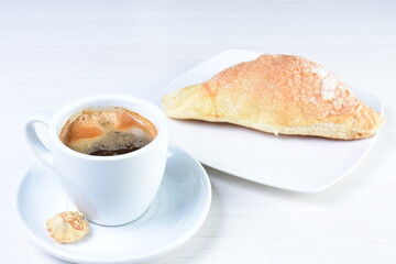 Cup of Colombian coffee, accompanied by baked bakery on white wooden background