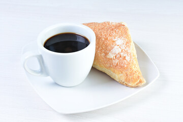 Cup of Colombian coffee, accompanied by baked bakery on white wooden background