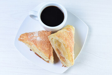 Cup of Colombian coffee, accompanied by baked bakery on white wooden background