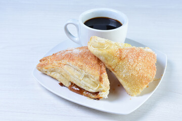 Cup of Colombian coffee, accompanied by baked bakery on white wooden background