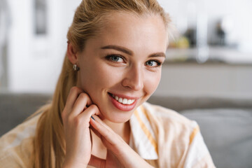 Happy blonde woman smiling and looking at camera at home