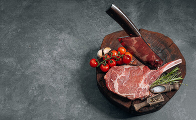 on a wooden block for meat a fresh raw tamahawk steak or a cowboy steak with a butcher's chopping...