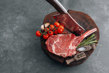 on a wooden block for meat a fresh raw tamahawk steak or a cowboy steak with a butcher's chopping...